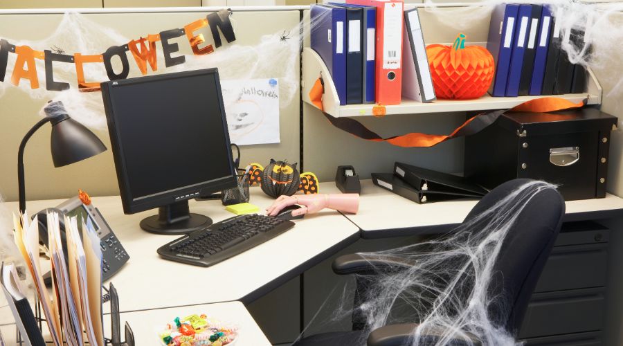 cubicle decorated for halloween with pumpkins and spiderwebs