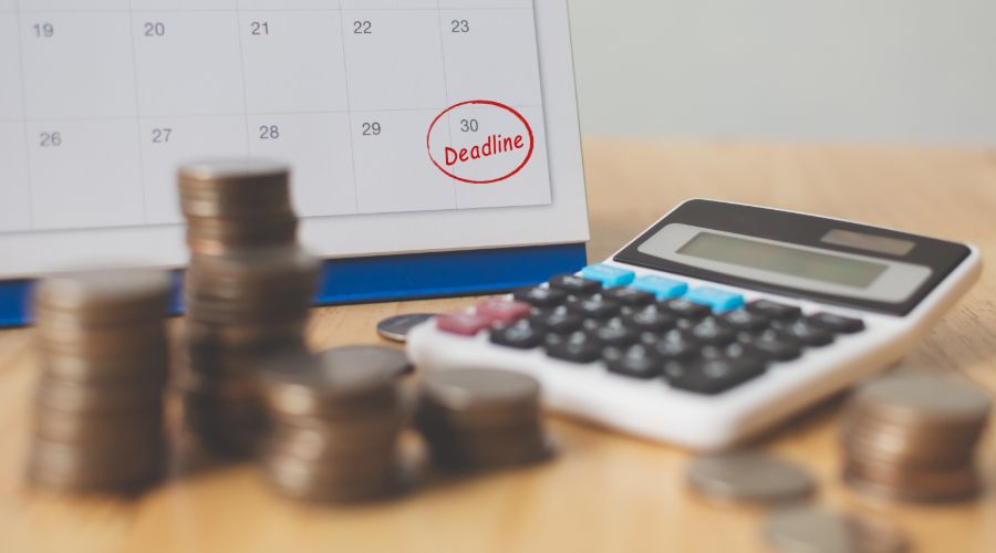 calculator and change with calendar in the background with deadline circled