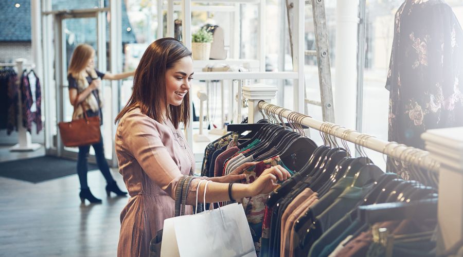 woman smiling while shopping for clothes in a store