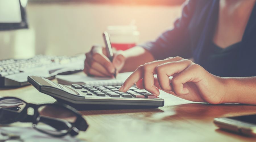 woman using a calculator to determine payroll taxes