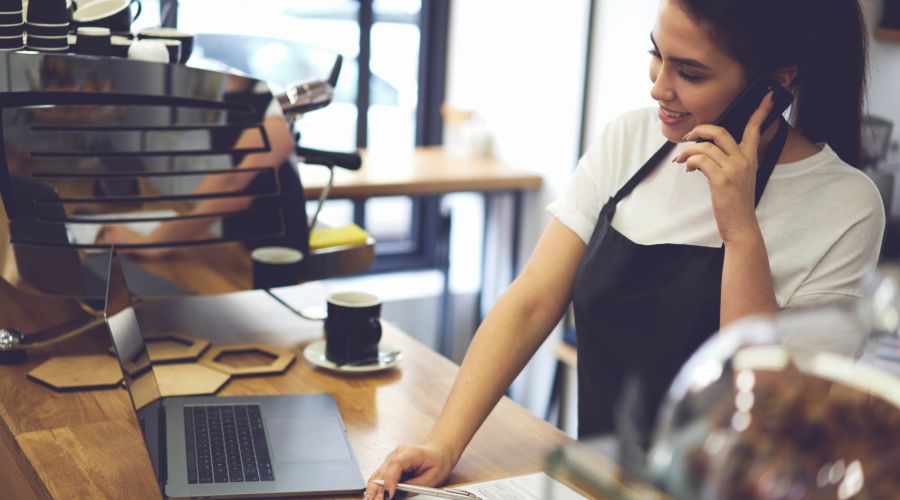 female coffee-shop franchisee talking on the phone while exploring payroll options